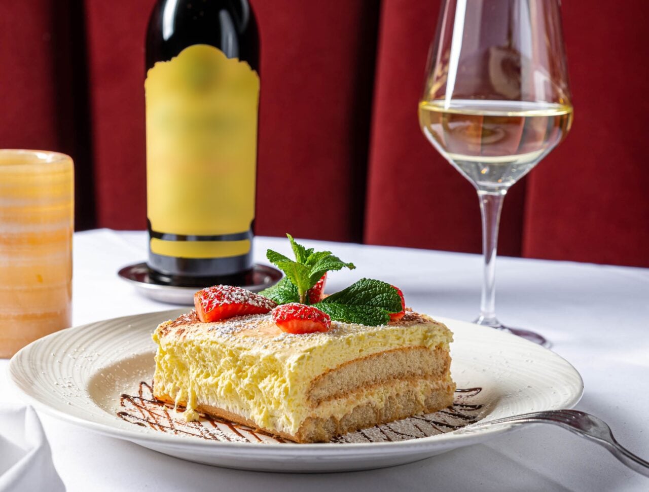 Tiramisu dessert with a bottle and glass of white wine at Rosebud Steakhouse